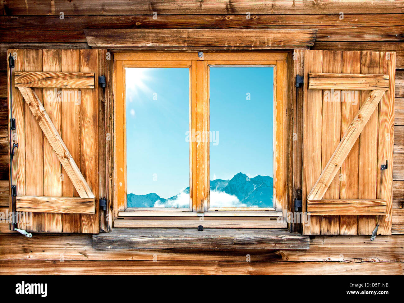 Weathered facciata di una baita di montagna con la riflessione di montagna nella finestra Foto Stock
