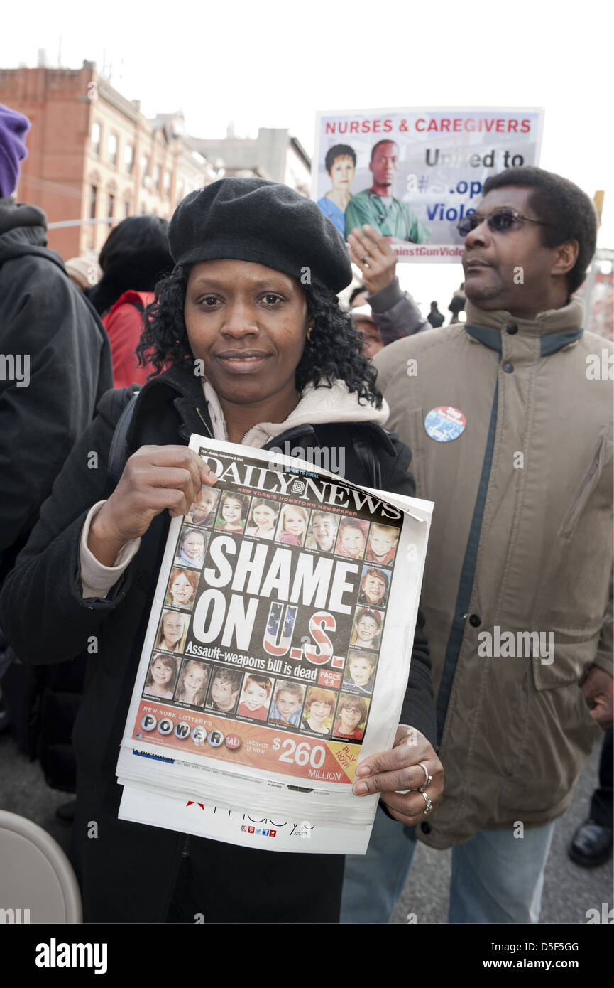 Anti-gun rally nel quartiere di Harlem di Manhattan, il 21 marzo 2013. Donna che mantiene un giornale che mostra Sandy Hook vittime. Foto Stock