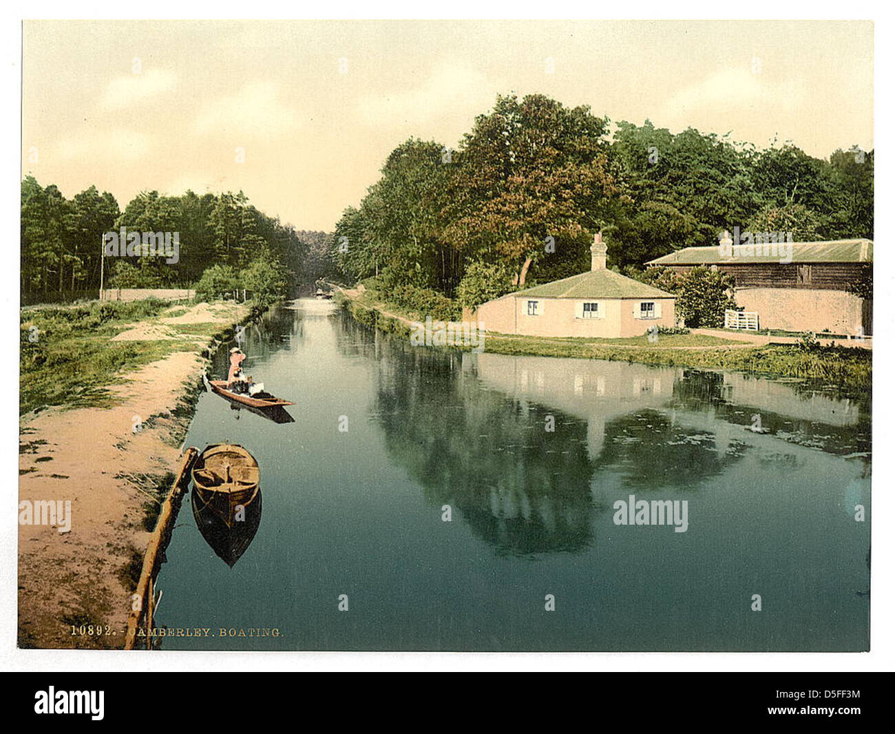 Questa fotografia cattura l'attività di nautica su un canale navigabile a Camberley, in Inghilterra. La scena raffigura le barche che viaggiano lungo un canale, mostrando lo stile di vita tranquillo e rurale del tempo. Foto Stock