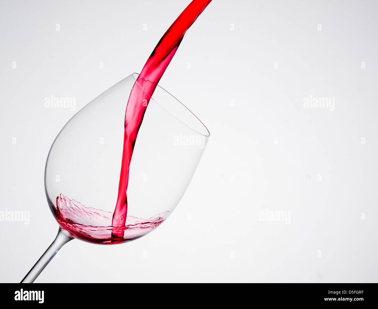 Versando il vino in un vetro di composizione diagonale e sfondo bianco Foto Stock