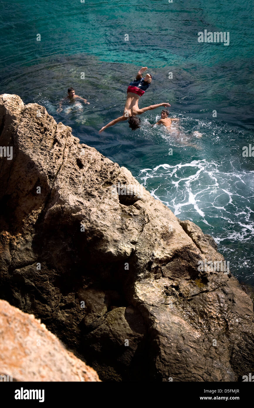 I bambini con un tuffo nel mare da una roccia in Ibiza Foto Stock