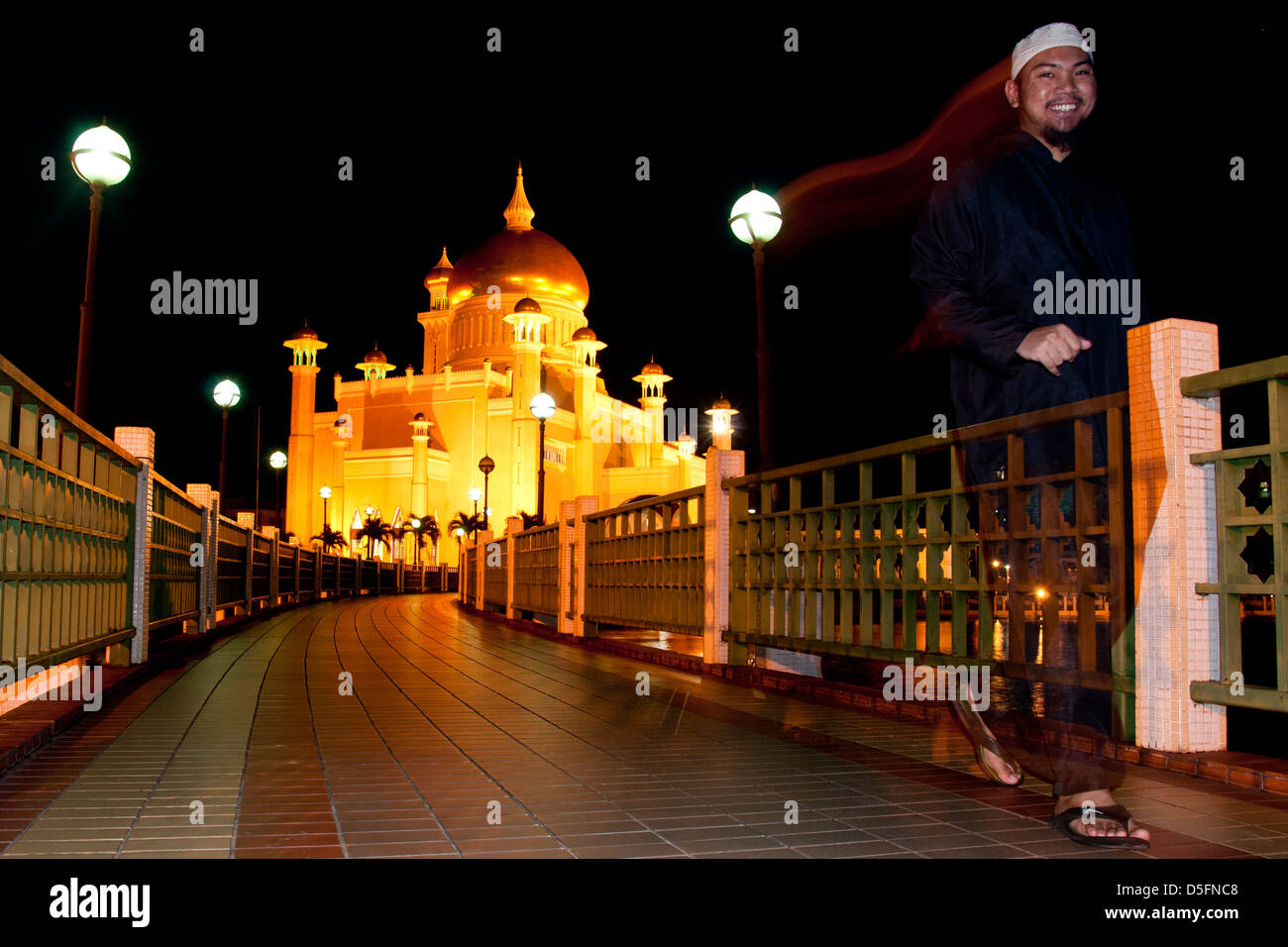 Musulmani felici a piedi nella parte anteriore del sultano Omar Ali Saifuddin Moschea di notte Foto Stock