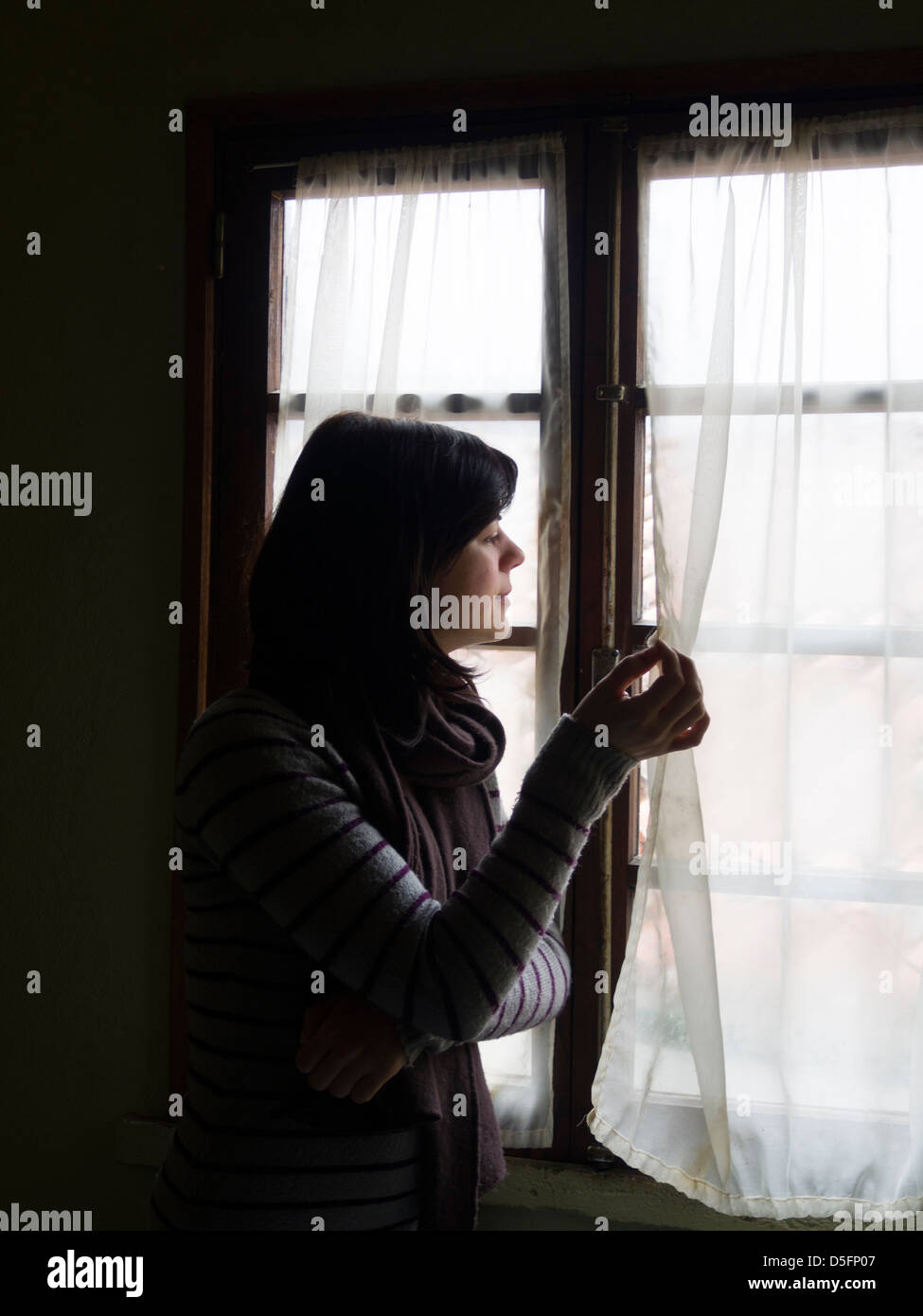 Donna che guarda fuori della finestra Foto Stock