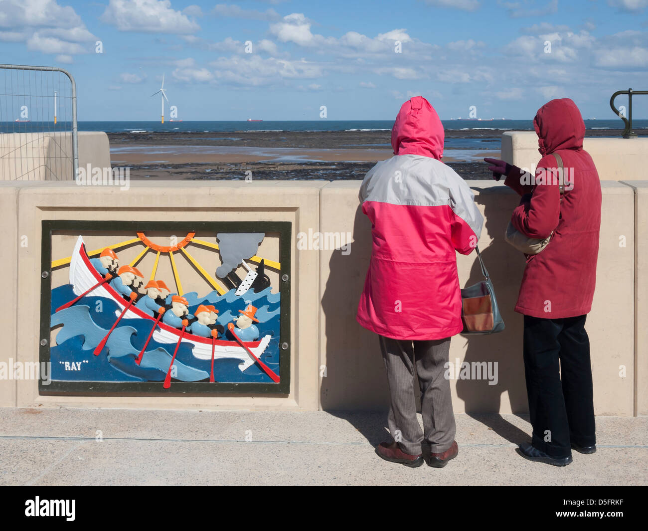 Due anziane signore con abiti caldi contro il gelido vento guardare oltre il mare nuovo muro a Redcar Foto Stock