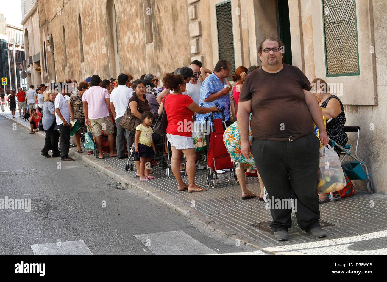 A disoccupati o a bassa risorse persone attendere alla porta di un centro di carità per un sacco di beni. Foto Stock