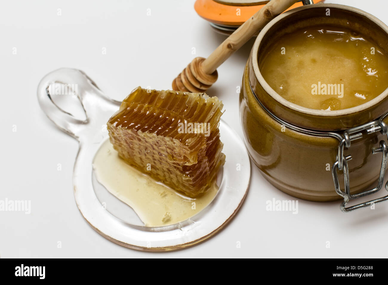 Il dolce miele nella pentola con il nido e bastone di legno Foto Stock