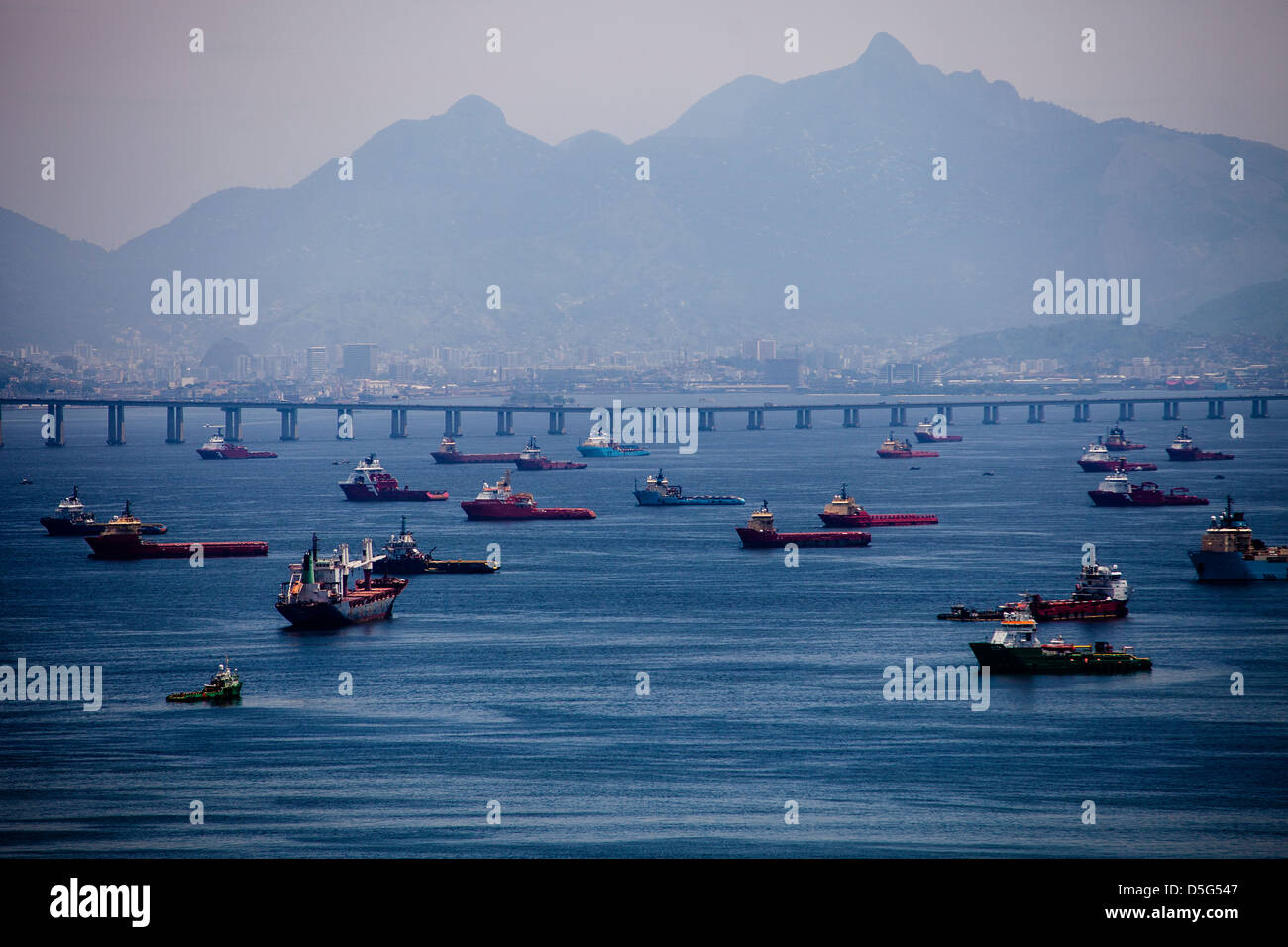 Vista aerea di intenso traffico marittimo nella baia di Guanabara, Rio de Janeiro, Brasile, dove petroliere e navi da carico, e le navi di supporto dominano le acque. La baia, un centro vitale per il trasporto marittimo e la logistica petrolifera, deve affrontare le sfide ambientali in corso a causa della proliferazione urbana, delle acque reflue non trattate, dei rifiuti solidi e delle perdite di petrolio ricorrenti, che minacciano tutti i suoi ecosistemi marini e la qualità delle acque. Foto Stock