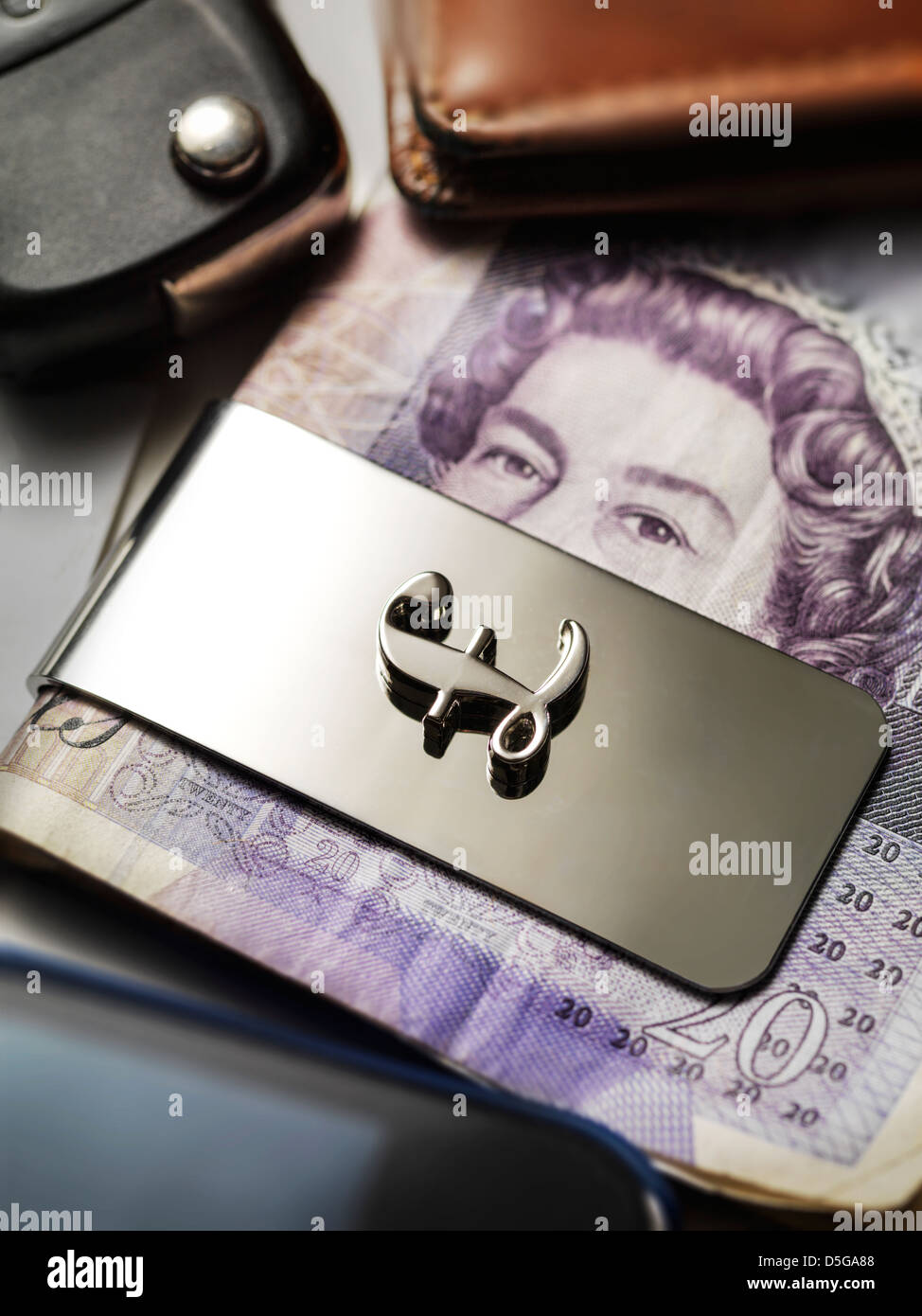 Un 20 Pound sterling nota tiene dietro una clip di denaro che ha il simbolo cancelletto su di esso su una scrivania riempito con oggetti casuali Foto Stock