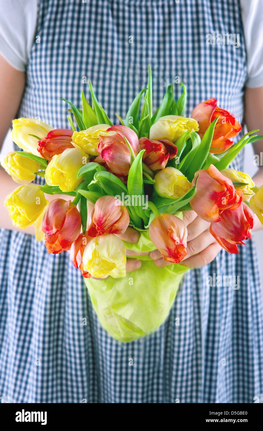 Bambina abiti estivi di consegnare un bouquet di giallo e arancione i tulipani Foto Stock