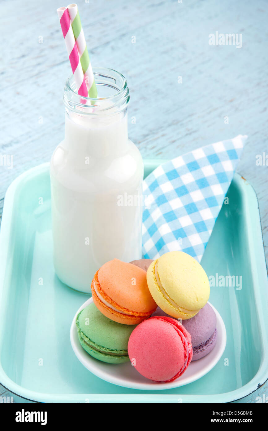 Impostazione vintage del pastello colorato gli amaretti e il latte in una bottiglia con cannucce a strisce Foto Stock