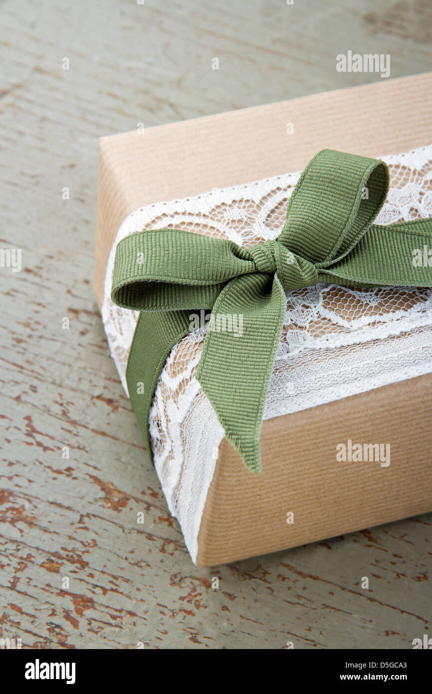 Decorazione semplice scatola regalo fasciata in marrone eco carta pizzo bianco e verde sulla prua di legno sfondo vintage Foto Stock