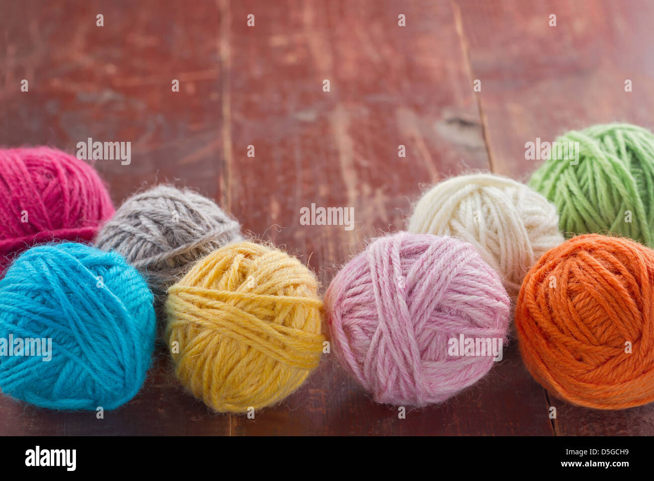 Coloratissime palle di filati di lana sul vecchio vintage in legno rosso sfondo - sfondo di lavorazione a maglia Foto Stock