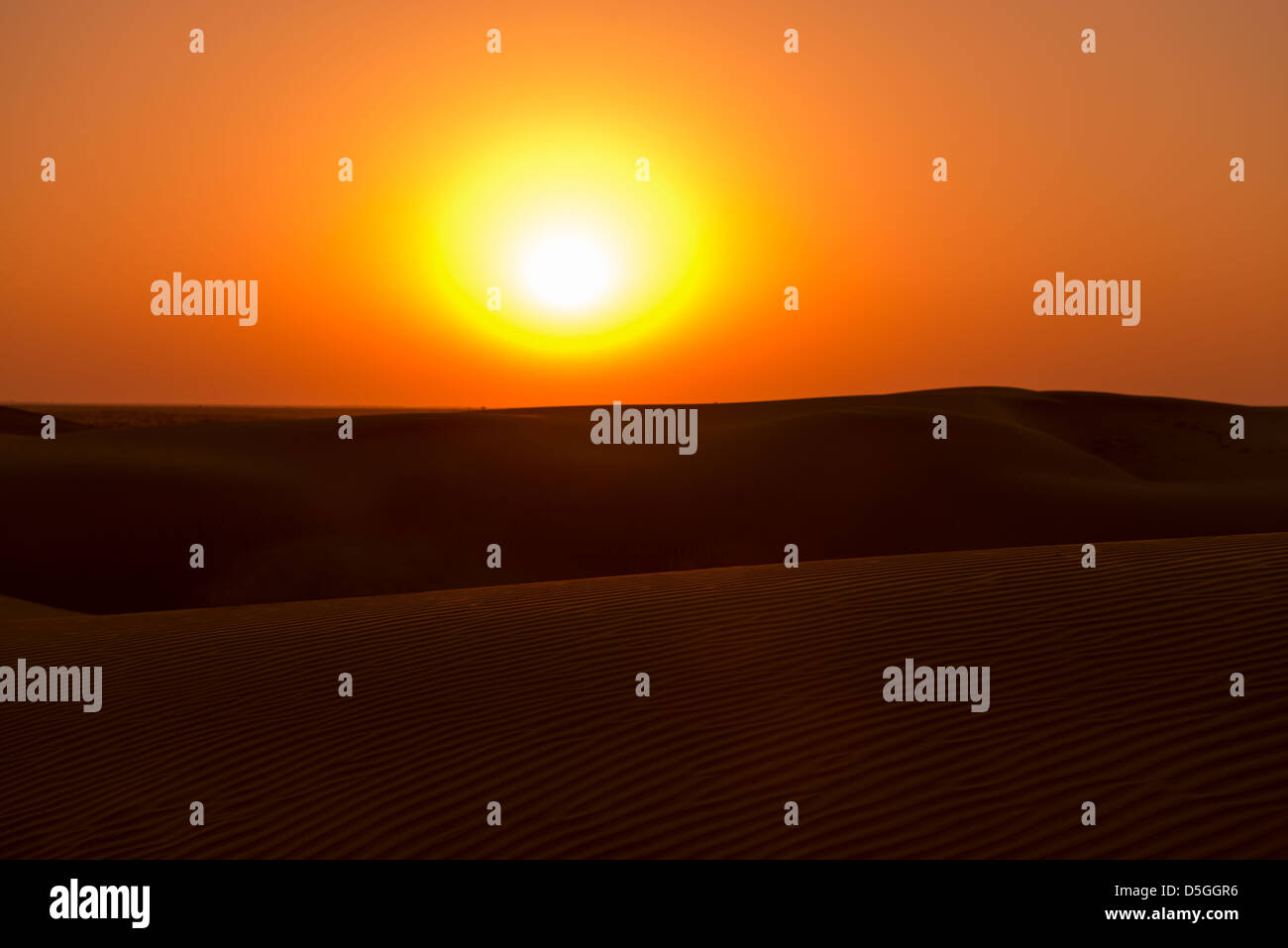 Grande giallo sole sotto le dune di sabbia nel deserto al tramonto. Deserto di Thar o Grande deserto indiano. Foto Stock