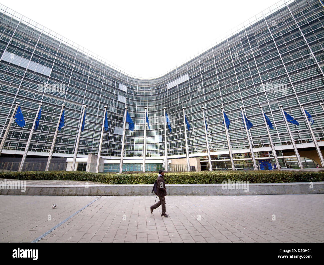 Lone uomo nero oltrepassando la enorme europea Berlaymont edificio della Commissione a Bruxelles, in Belgio Foto Stock