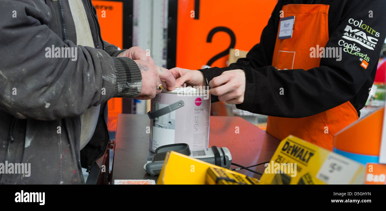 Un uomo di acquistare un vaso di vernice da un negozio assistente presso una filiale di B&Q DiY superstore shop hardware azienda retail UK Foto Stock