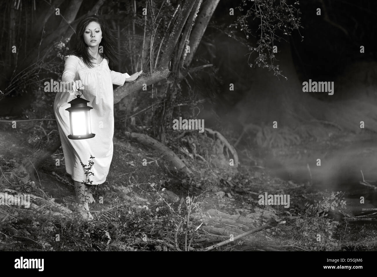 Donna con la lanterna nel bosco Foto Stock