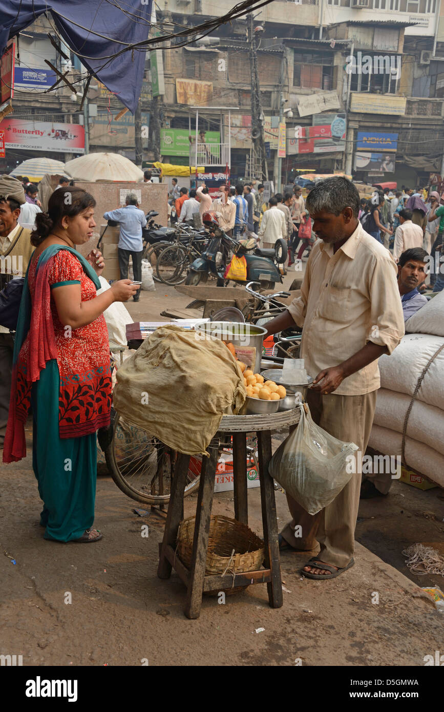 Una donna di acquistare alcuni prodotti alimentari da un prodotto alimentare in stallo Khari Baoli Road, Chandni Chowk,Vecchia Delhi, India Foto Stock