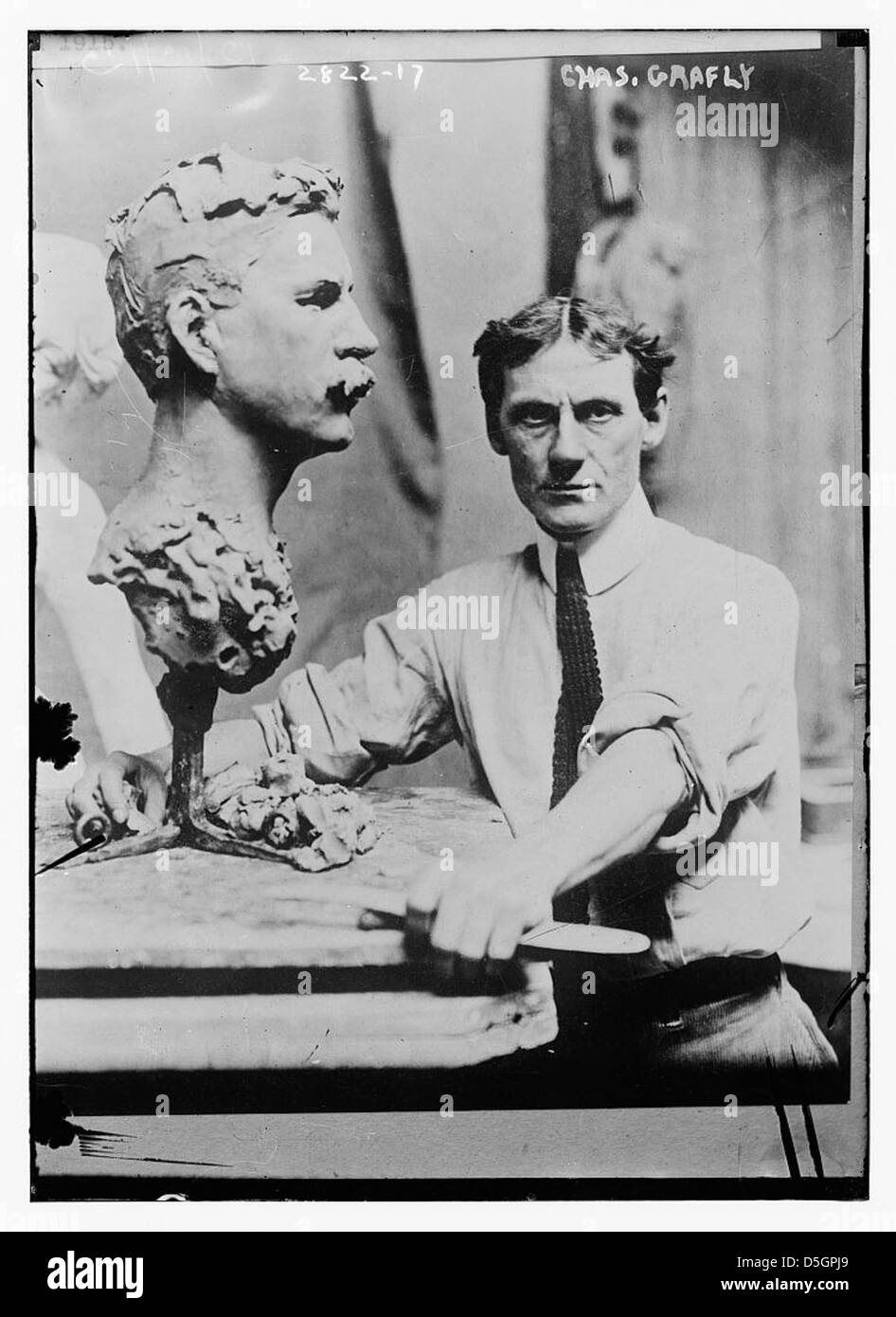 Charles Grafly, un notevole scultore americano, è raffigurato al lavoro su una scultura di argilla. Grafly era noto per le sue belle sculture artistiche e per i suoi contributi alla scultura americana, in particolare con busti e sculture di ritratti. Le sue opere sono influenti nello sviluppo dell'arte e della scultura americana del XX secolo. Foto Stock
