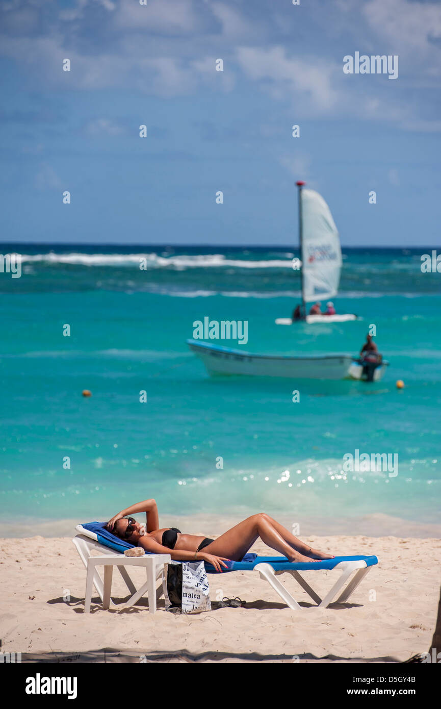 Repubblica Dominicana, Punta Cana, Higuey, Bavaro, Bavaro Beach, giovane donna a prendere il sole, barca a vela Foto Stock