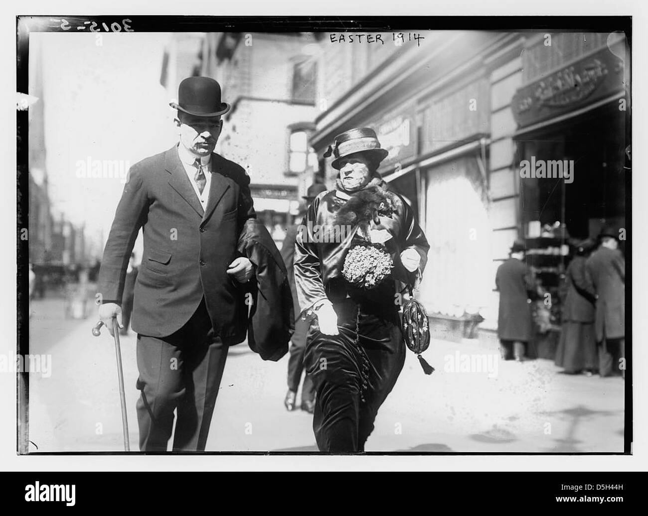 Una fotografia scattata la domenica di Pasqua, il 12 aprile 1914, sulla Fifth Avenue, New York City. L'immagine mostra un uomo e una donna che camminano per la strada con un mazzo di lillas, catturando la passeggiata alla moda del tempo. Foto Stock
