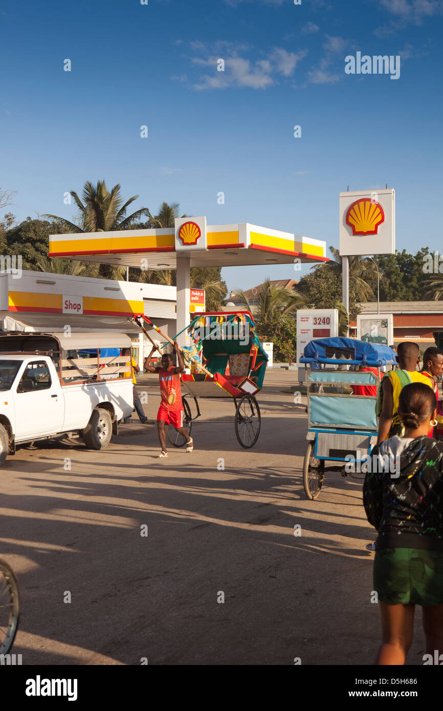 Madagascar, Toliara, pousse-pousse human powered rickshaw passando Shell stazione di benzina Foto Stock