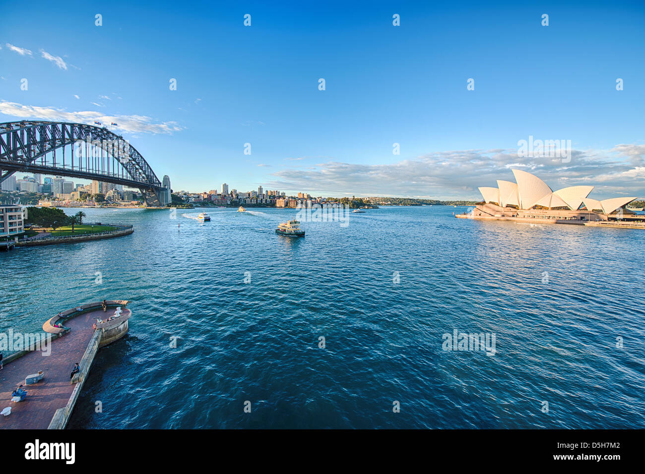 Traghetti passano tra il maestoso Sydney Opera House e il Sydney Harbour Bridge. Foto Stock