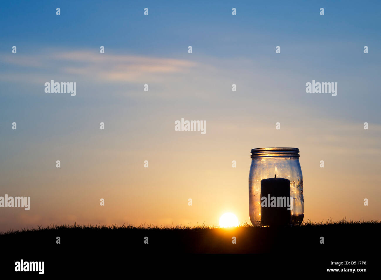 Candela in un barattolo di vetro a sunrise. Silhouette Foto Stock