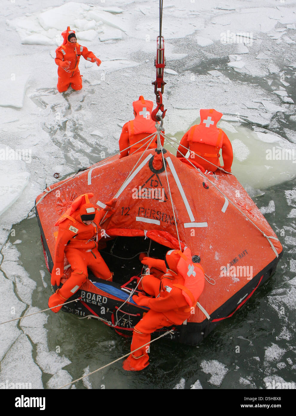 I membri del personale di navi da crociera a esercitare il diritto di comportamento in tute di sopravvivenza nel Warnow a Rostock, Germania, 09 febbraio 2010. L'esercizio è parte di una sicurezza di base corso che è obbligatoria per i non-nautici i membri del personale delle navi da crociera. L'Aus- und Fortbildungszentrum Schifffahrt und Hafen (AFZ, " formazione e istruzione centro per la spedizione e il porto') offre differenti ki Foto Stock