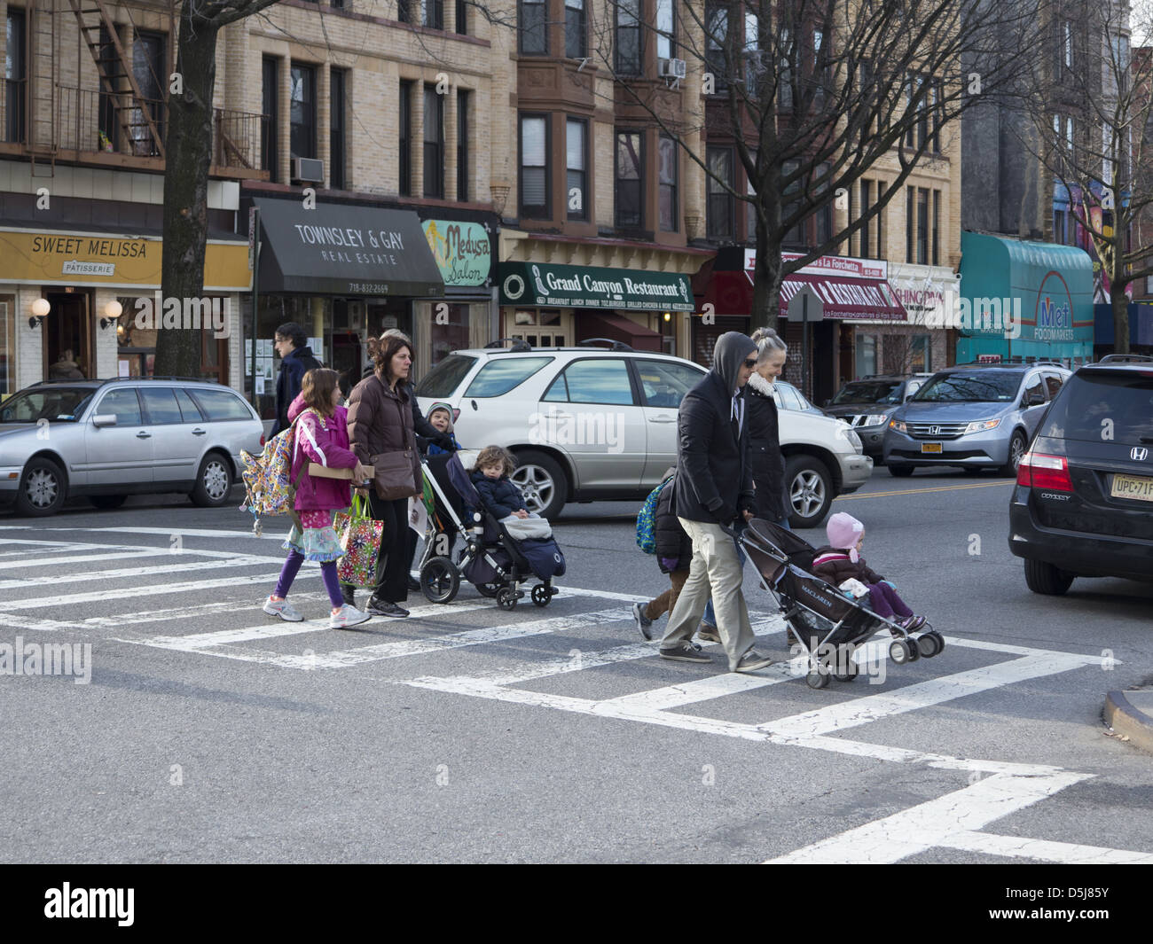 I genitori a piedi i loro bambini a scuola lungo 7 Ave. spingendo verso quelli più giovani in passeggini a Park Slope Brooklyn, NY Foto Stock