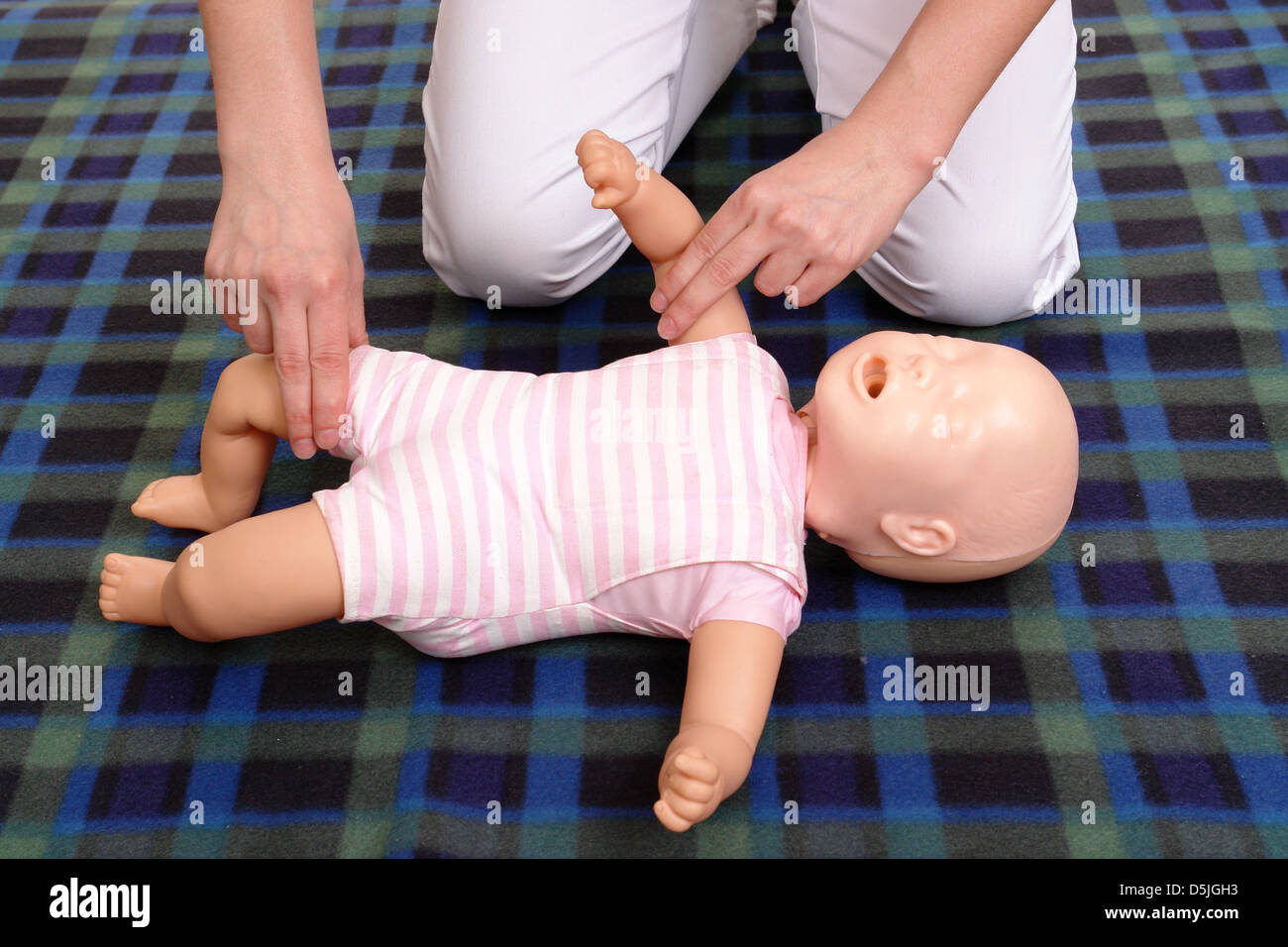 Primo soccorso istruttore che mostra come impulso di controllo sul manichino neonato Foto Stock