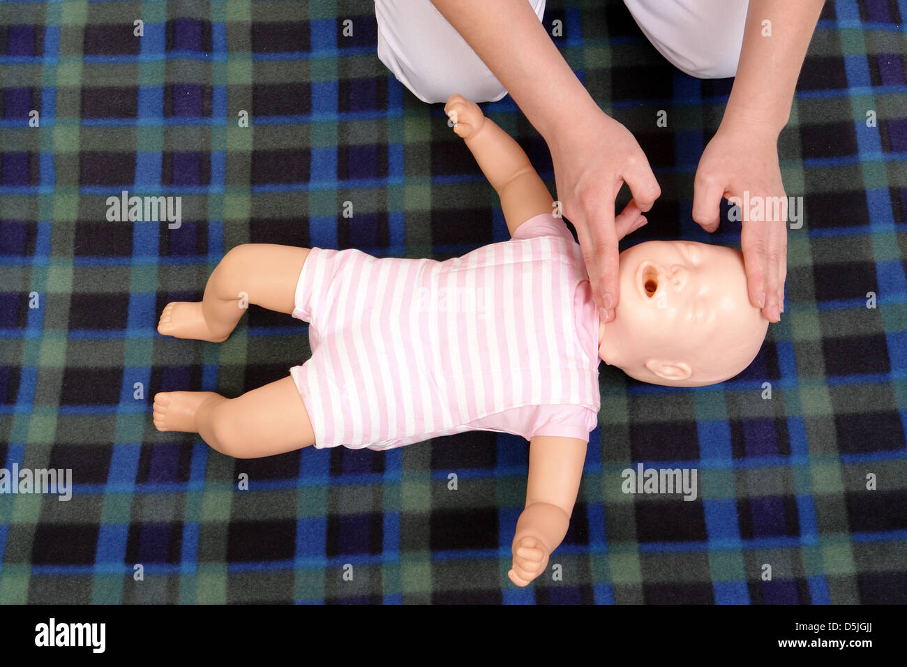 Primo soccorso istruttore che mostra come posizionare la testa per neonati prima di procedere con la bocca a bocca - rianimazione vista da sopra Foto Stock