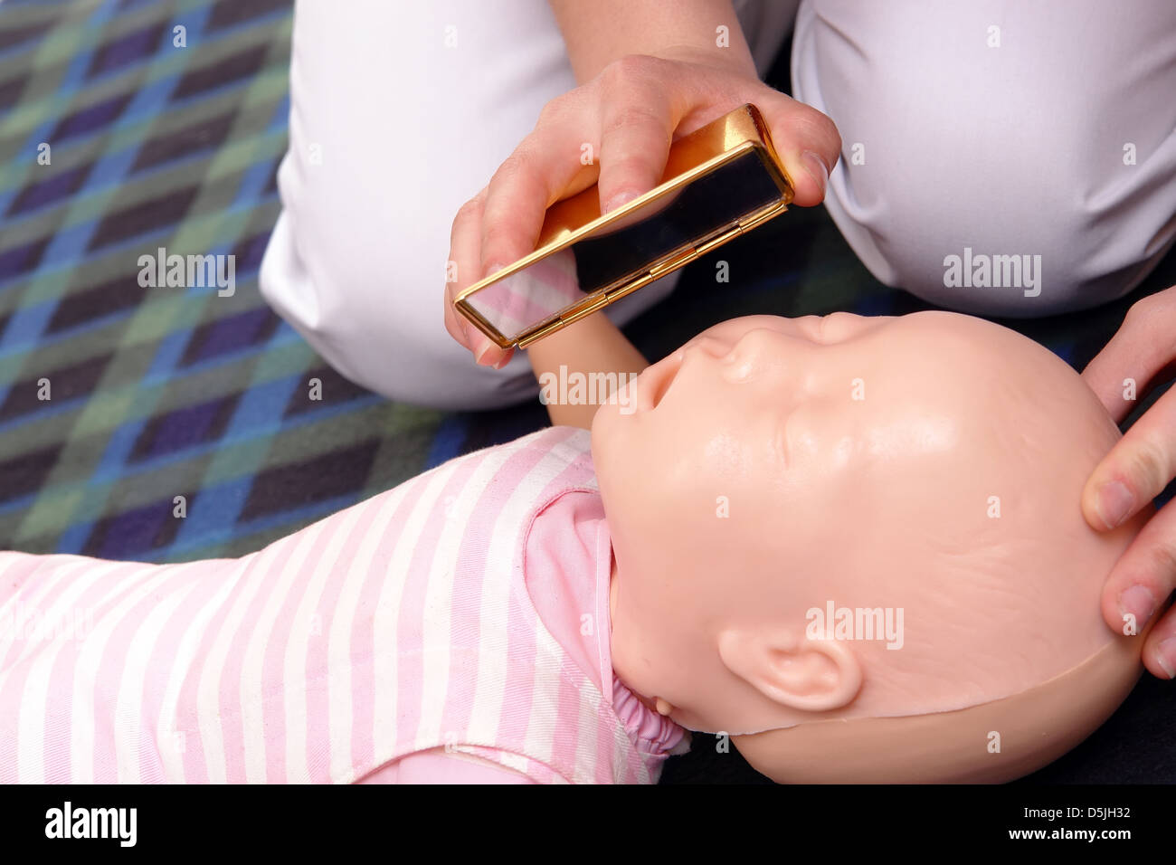 Primo soccorso istruttore dimostrando come controllare la vita infantile funzioni usando uno specchio Foto Stock