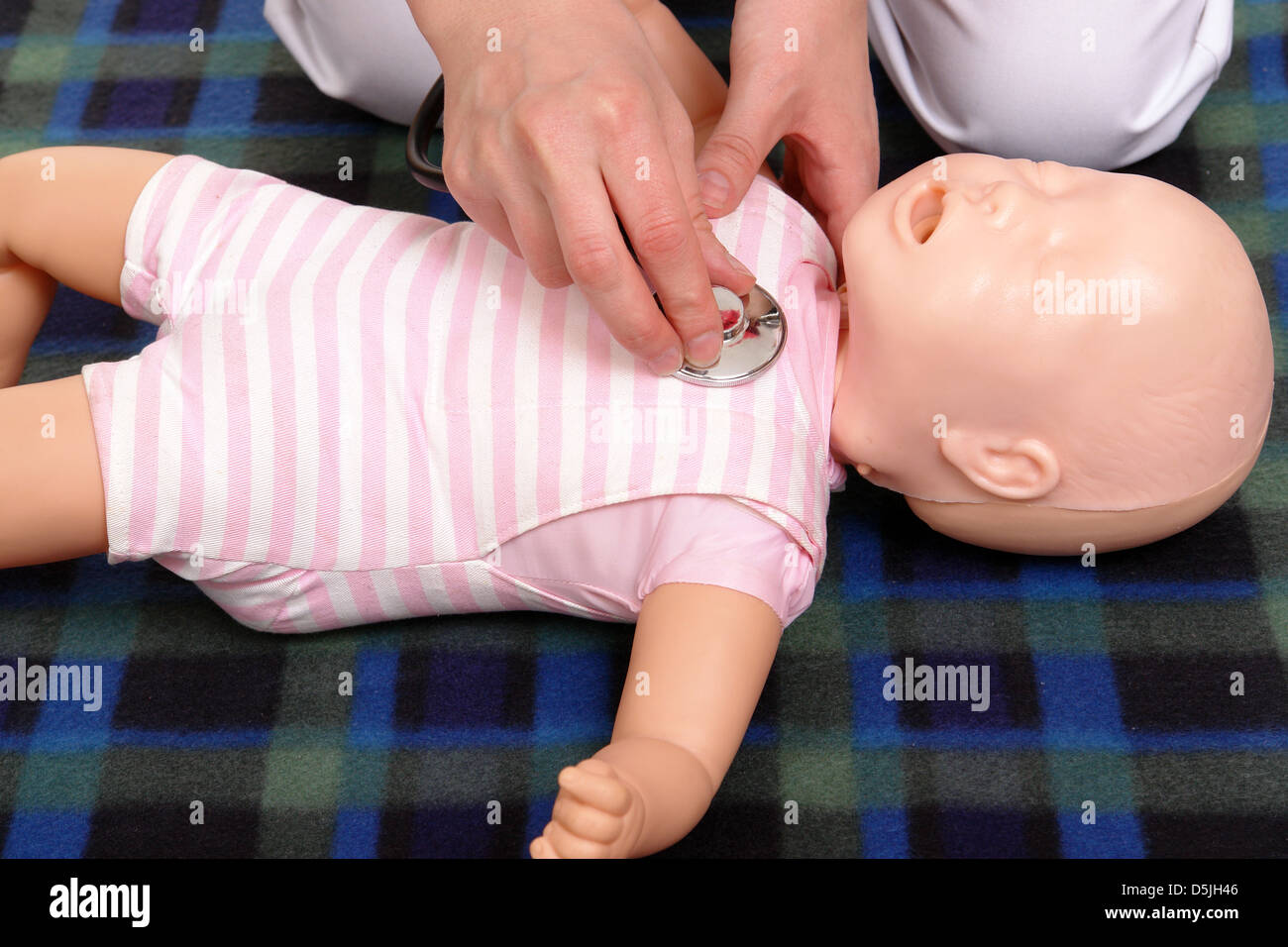 Primo soccorso istruttore utilizzando manichino neonato per dimostrare come esaminare bambino con uno stetoscopio Foto Stock