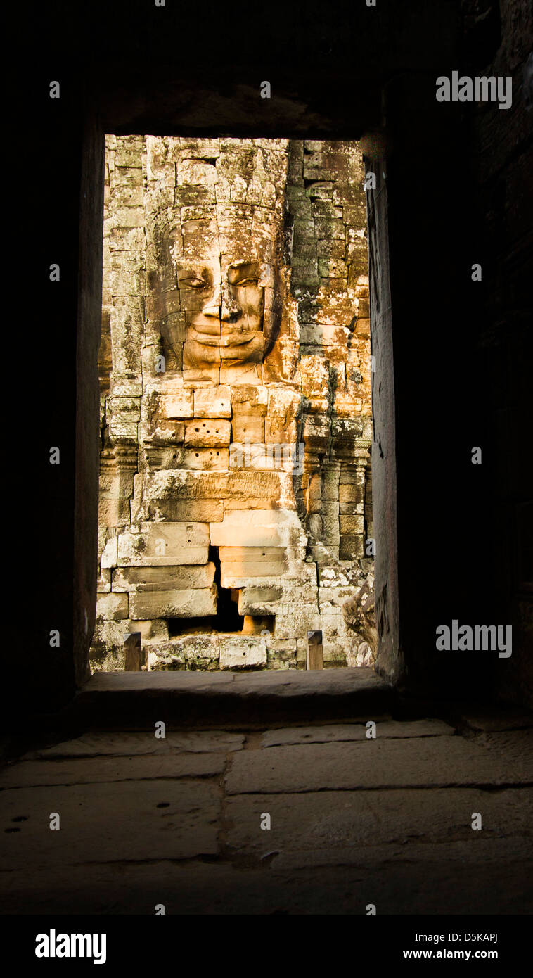 Buddha Sorridente al tempio Bayon in Cambogia visto attraverso una porta Foto Stock