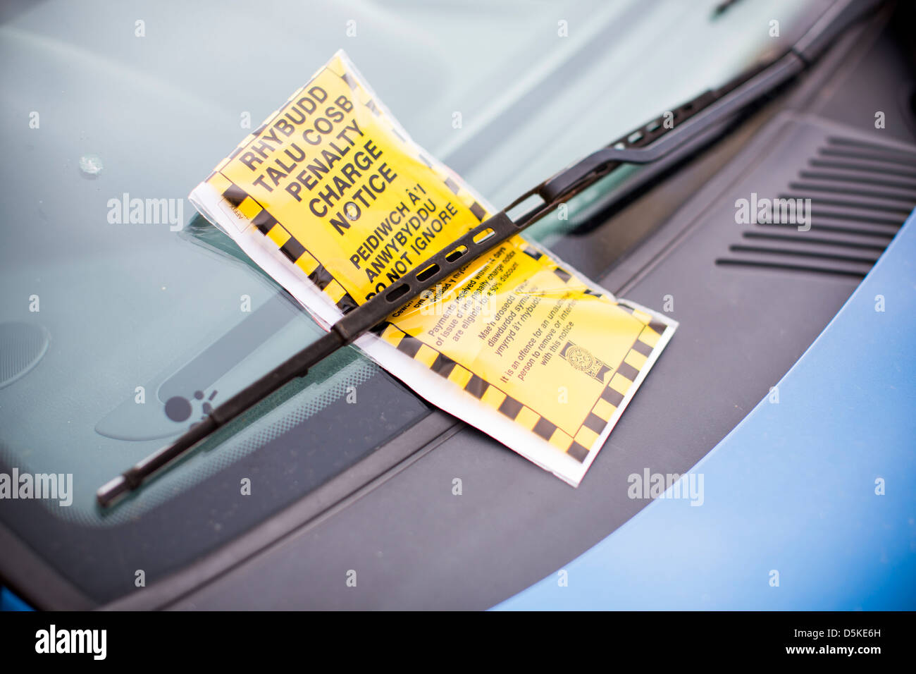 Una sanzione bilingue avviso di carica i biglietti per il parcheggio sia in inglese e gallese al disotto di un parabrezza di automobile del tergicristallo. Foto Stock