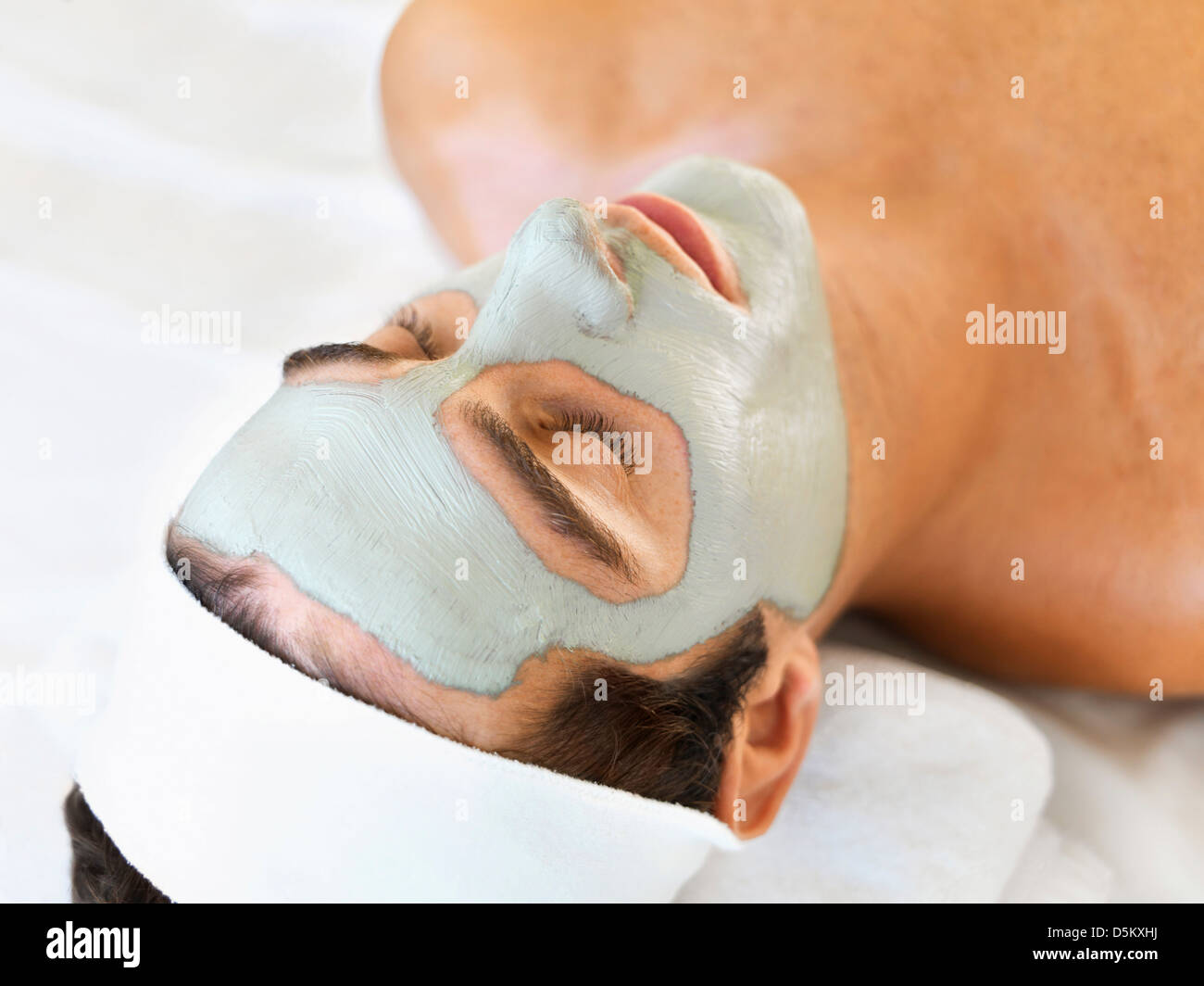 Uomo con la maschera per il viso rilassante nella spa Foto Stock