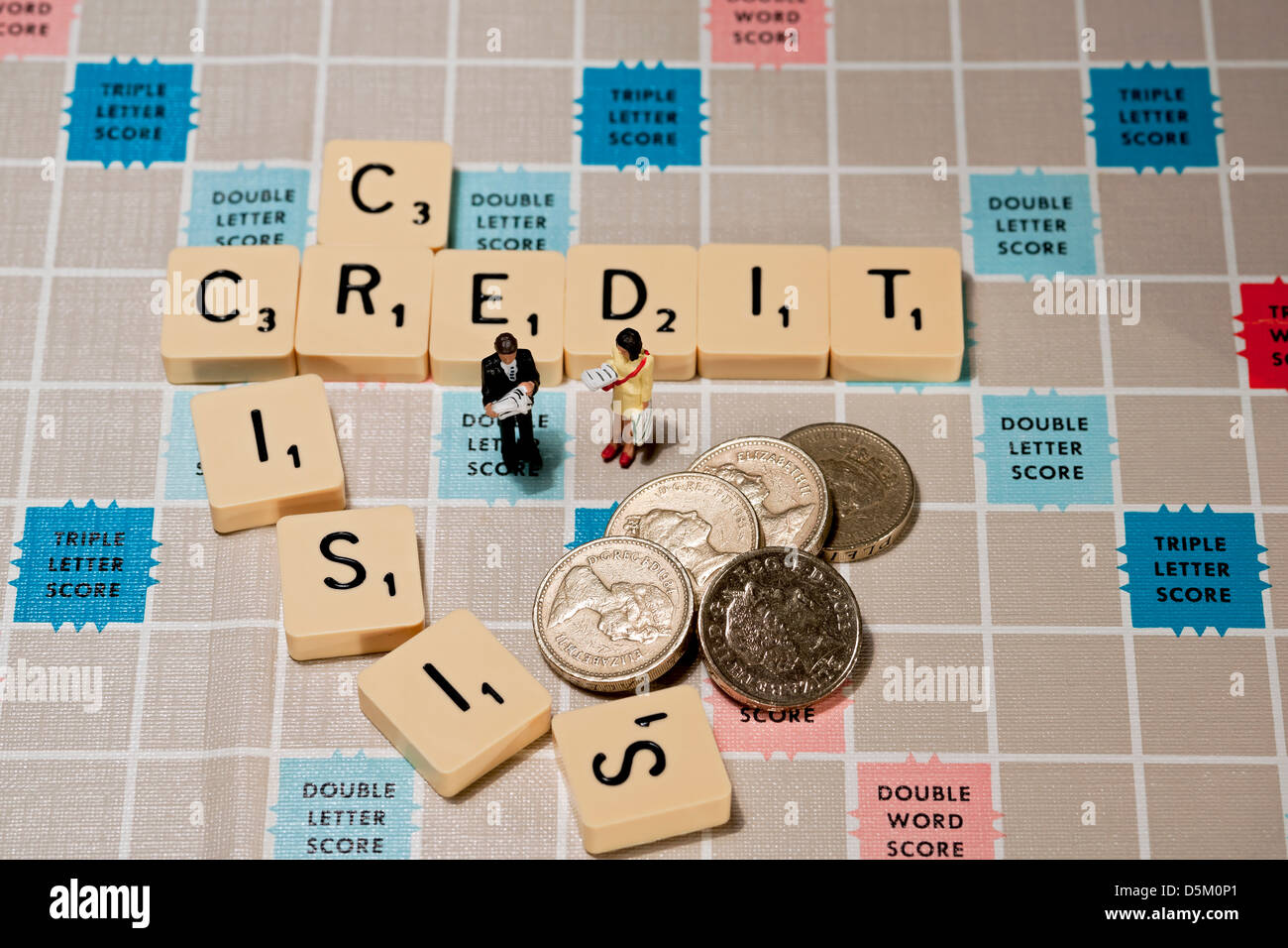 Piastrelle sulla lavagna di Scrabble che scrivono crisi creditizia, con uomo e donna giocattolo e concetto di finanza aziendale di recessione in contanti delle monete inglesi Foto Stock