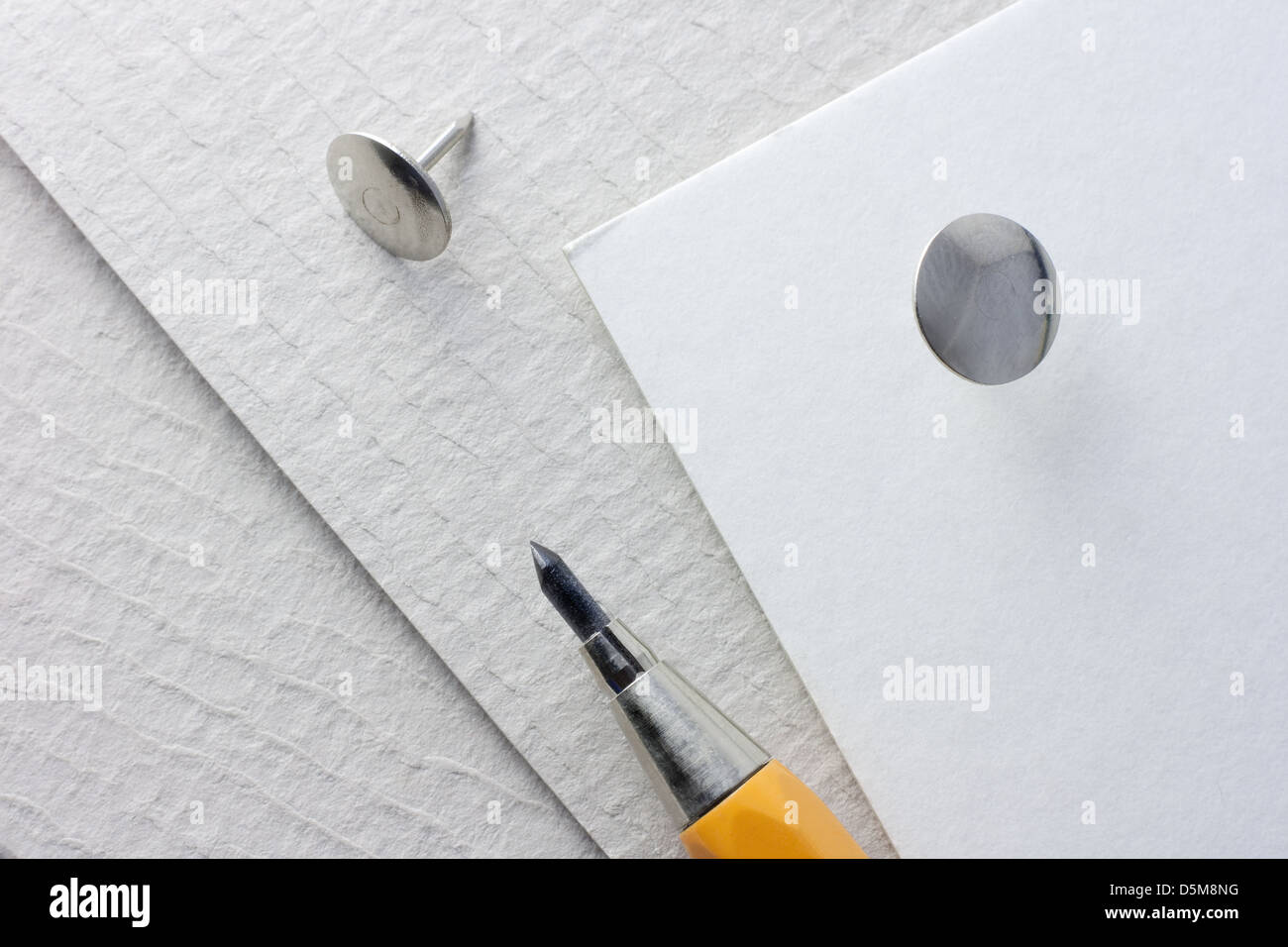 Matita meccanica e la puntina da disegno su un cartoncino grigio Foto Stock