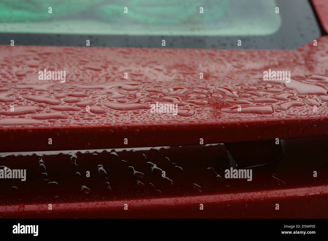 La pioggia di ala il riempimento di acqua di macchie d'acqua di colore rosso nella finestra colore auto Foto Stock