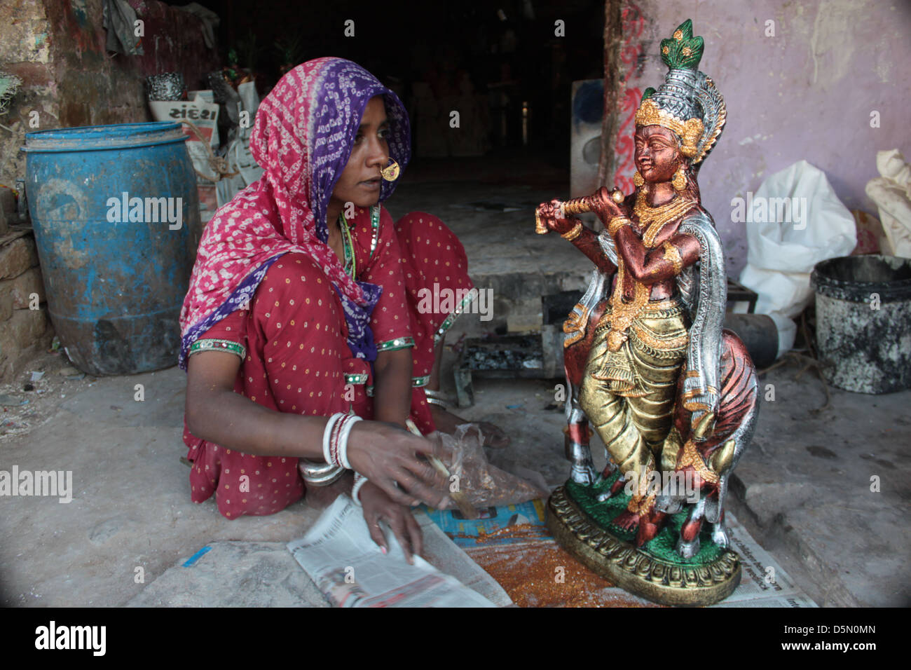 Una donna dà il tocco finale alle un idolo del dio indù Krishna, nel Gulbai Tekra località di Ahmedabad, Gujarat, India. Foto Stock