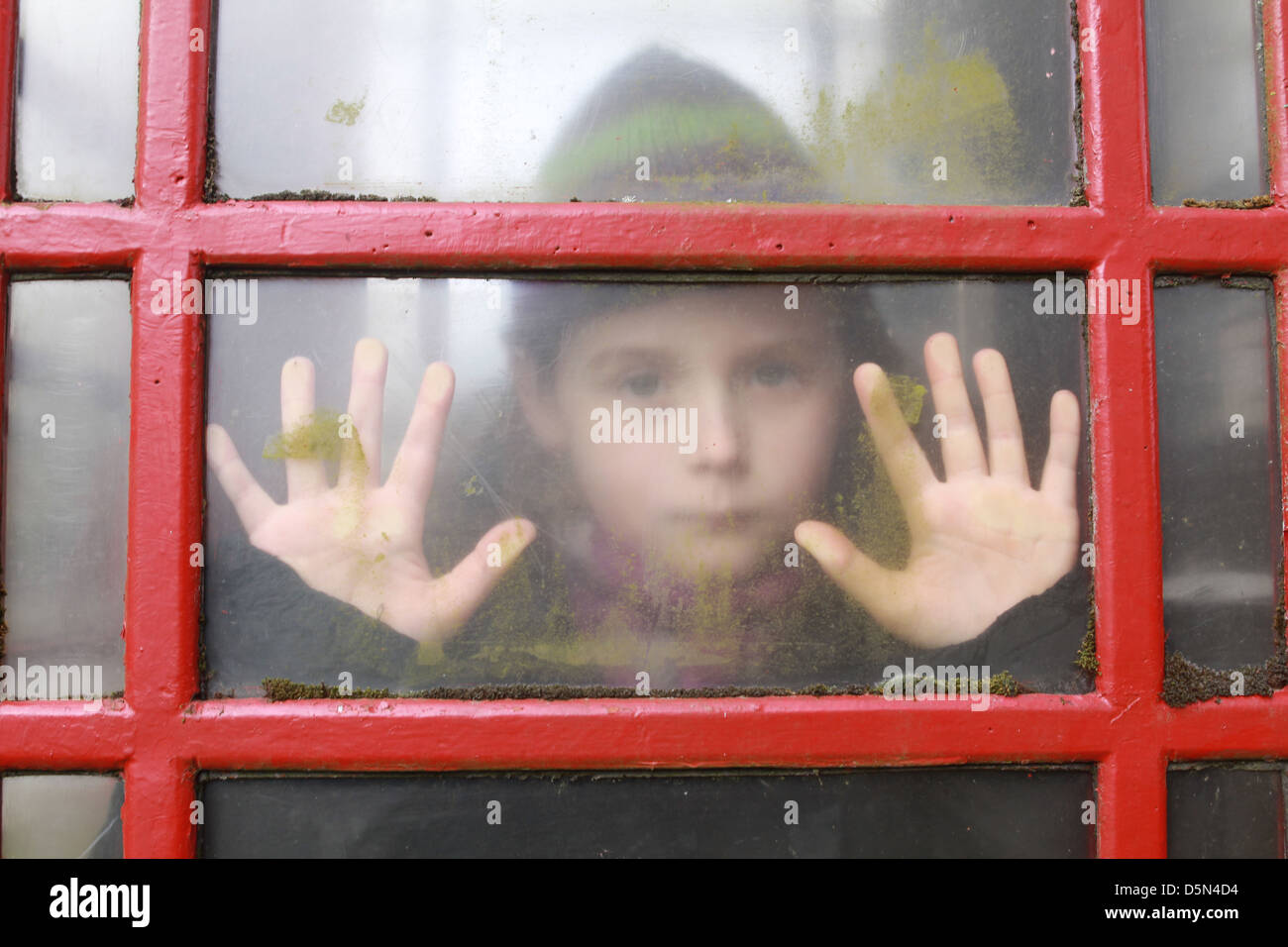 Bambino femmina fingendo di essere intrappolati in una casella telefono Foto Stock