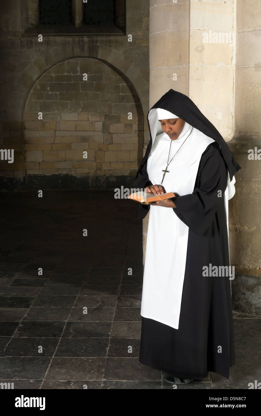 Nun in abitudine della lettura della Bibbia in una chiesa medievale Foto Stock