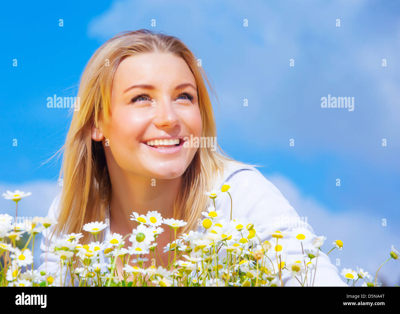 Closeup ritratto di carino donna bionda sul prato a margherita oltre il cielo azzurro sfondo, stagione primaverile, il concetto di felicità Foto Stock