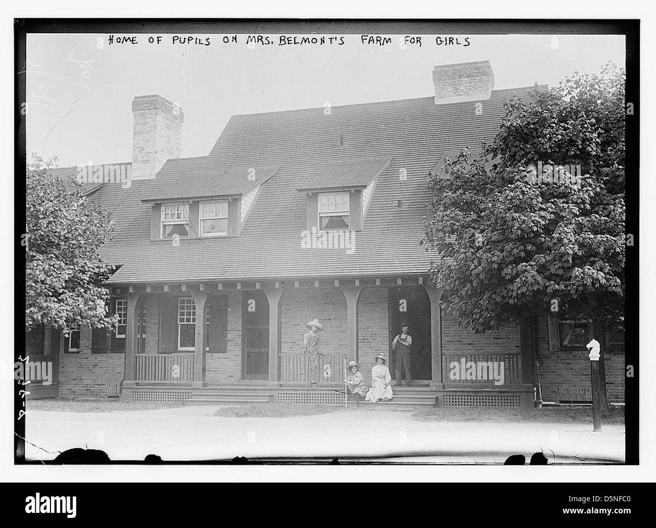 Una foto che mostra la casa per gli alunni della Farm for Girls della signora Belmont, situata a Hempstead, Long Island, New York. L'immagine cattura il design architettonico della casa colonica, con i suoi portici, camini e dintorni alberati, riflettendo l'ambiente educativo e residenziale per le ragazze all'inizio del XX secolo. Foto Stock