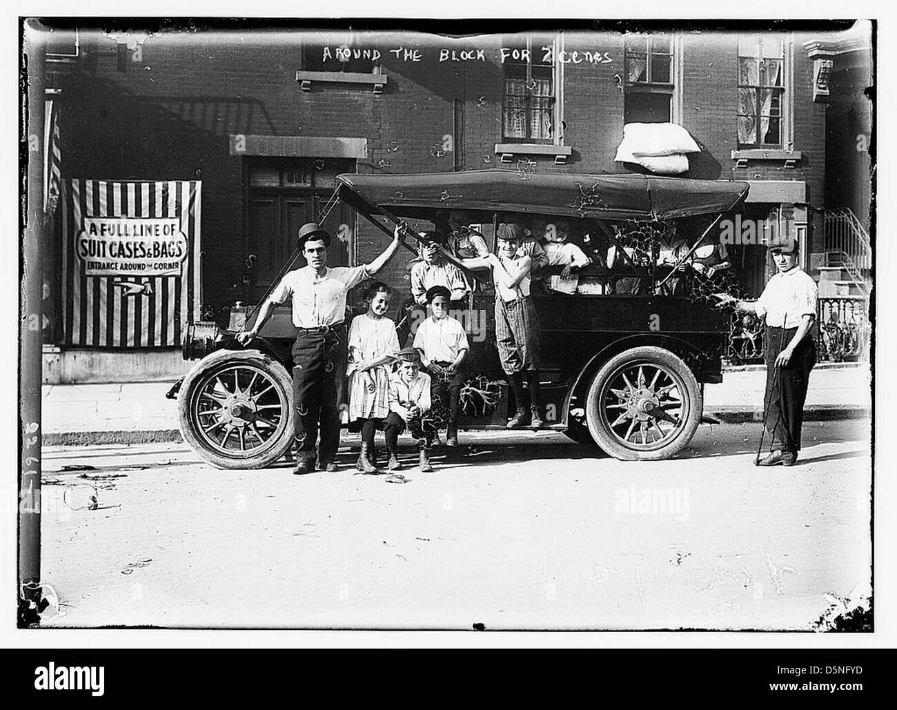 Una pubblicità vintage degli anni '1910 mostra un giro in auto intorno all'isolato per due centesimi, con bambini, uomini e valigie. L'annuncio cattura la prima cultura automobilistica in America e riflette il prezzo e l'attrattiva dei viaggi in auto durante il periodo. Foto Stock