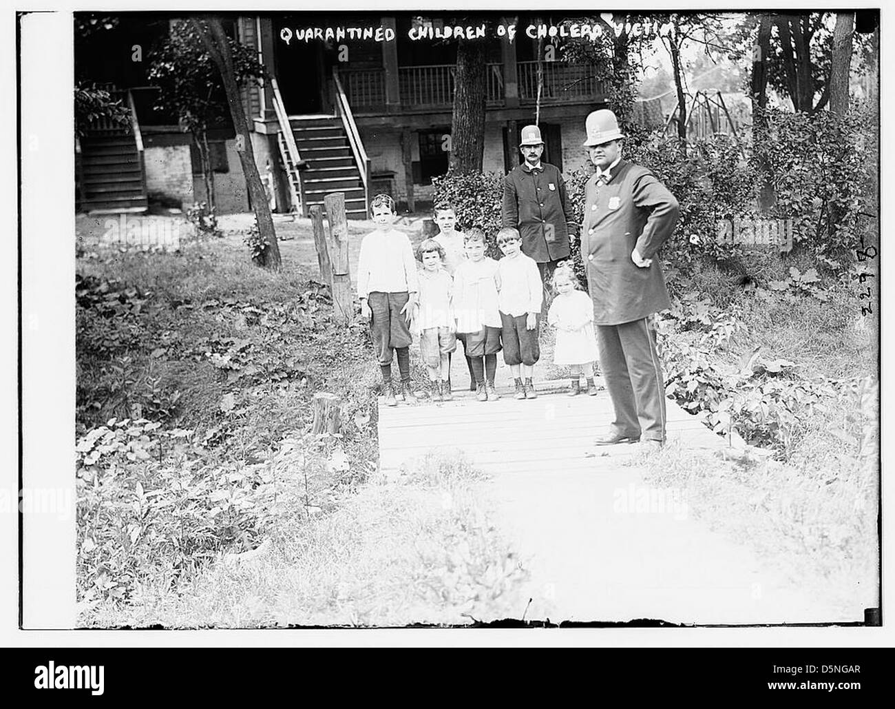 Questa immagine mostra i bambini in quarantena dopo essere stati esposti al colera, preso negli anni '1910 La foto cattura la triste realtà di un'epidemia di colera, con agenti di polizia che supervisionano la situazione. Foto Stock