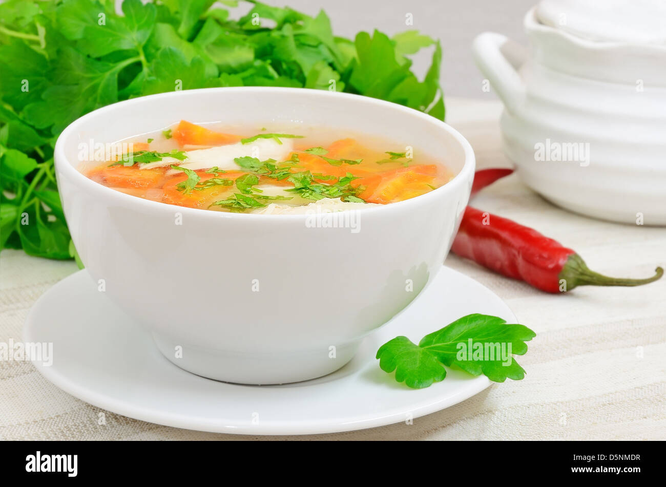 Zuppa di pollo con verdure in bianco ciotola su un tavolo Foto Stock