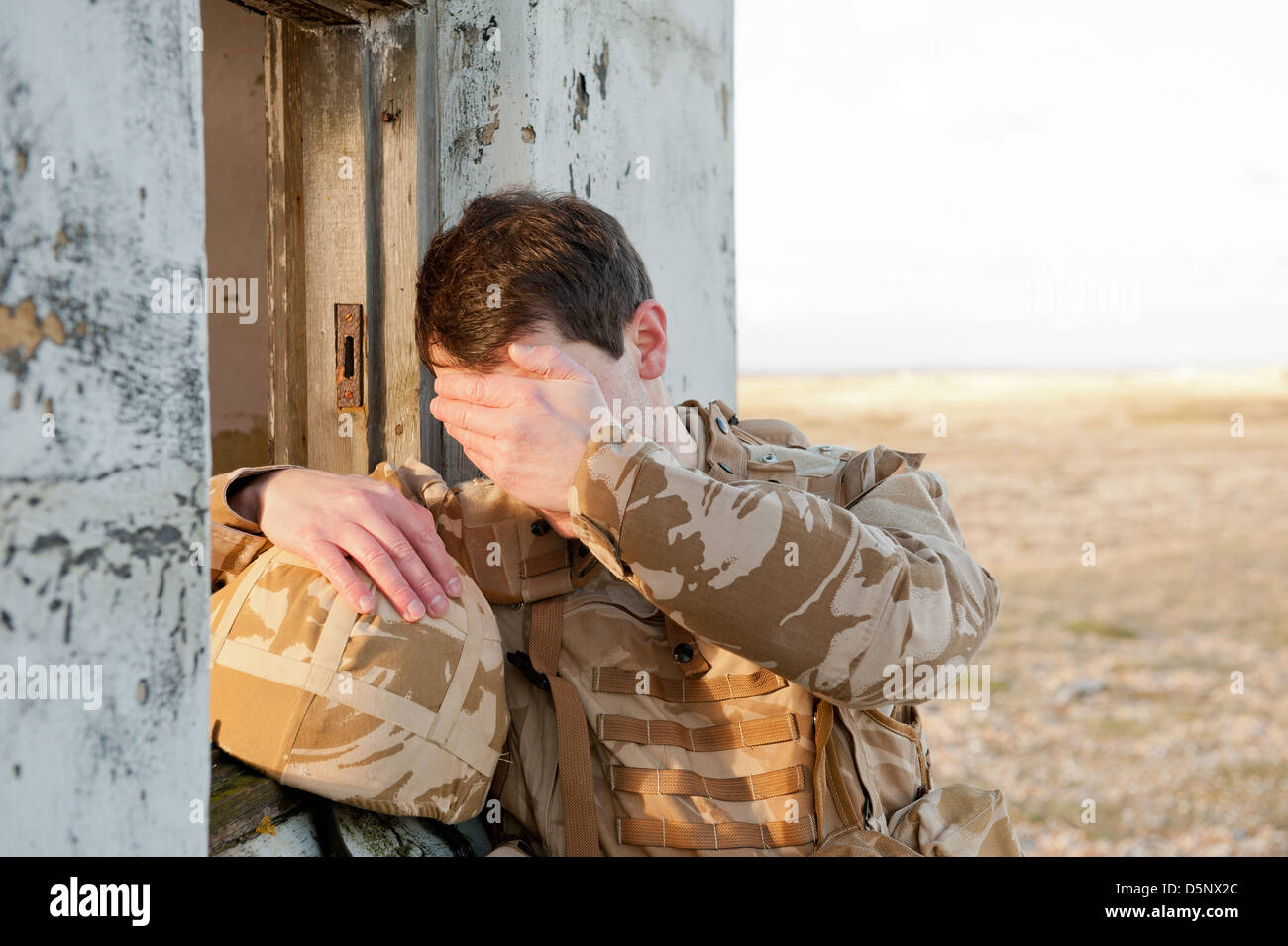 Soldato sofferenza con proprio Disturbo Post-traumatico da Stress sul campo di battaglia. Soldato indossa militare britannico uniforme del deserto. Foto Stock