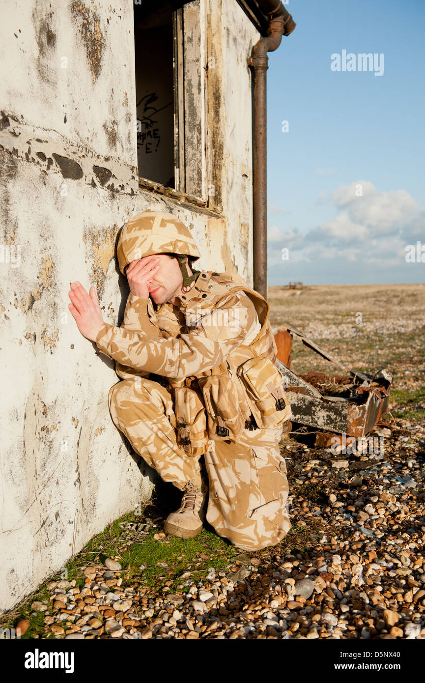 Soldato sofferenza con proprio Disturbo Post-traumatico da Stress sul campo di battaglia. Soldato indossa militare britannico uniforme del deserto. Foto Stock