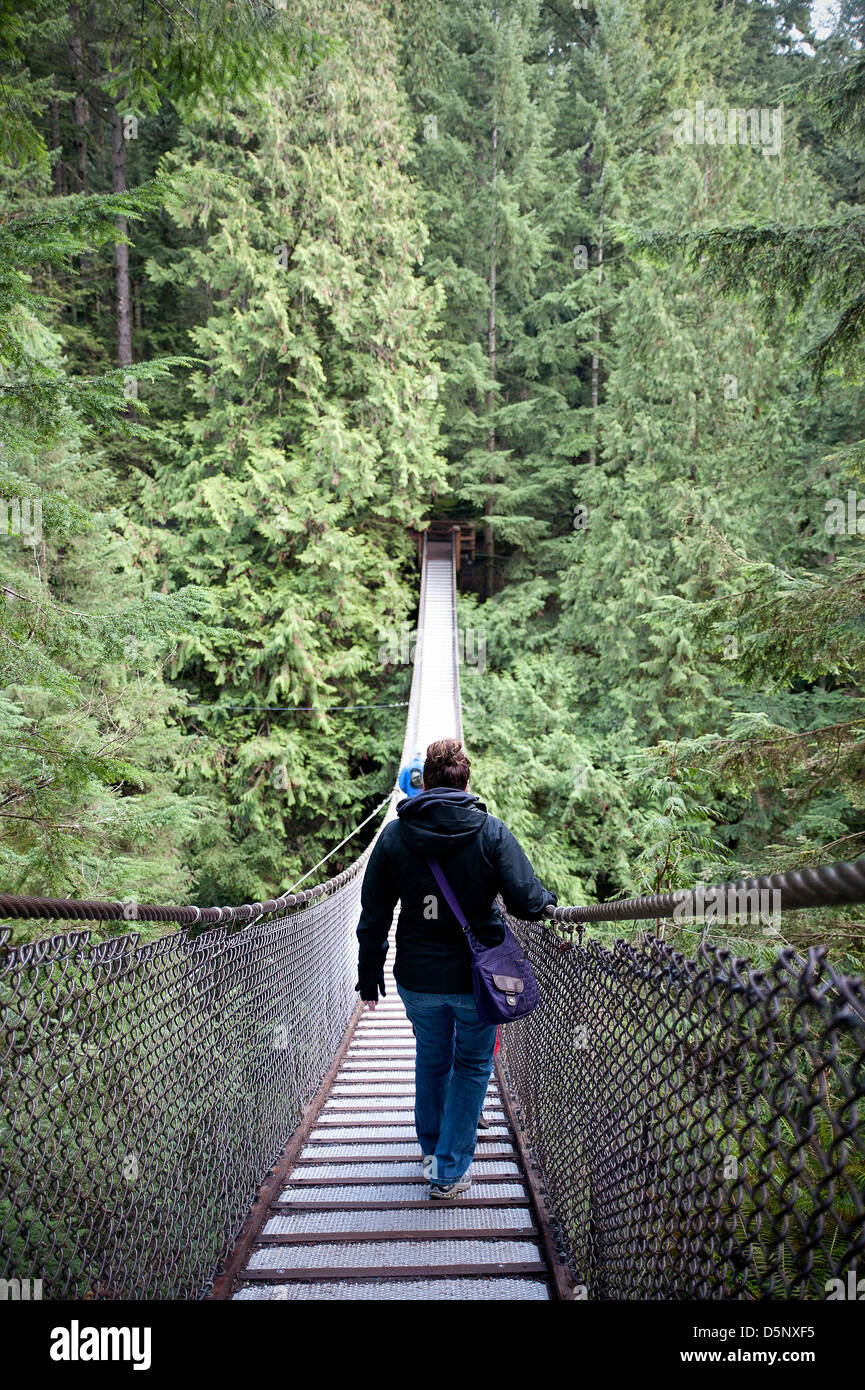 Donna attraversando ponte di sospensione. Foto Stock